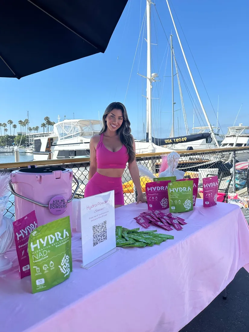 Lauren behind a Hydra Powders sampling table at a marina.